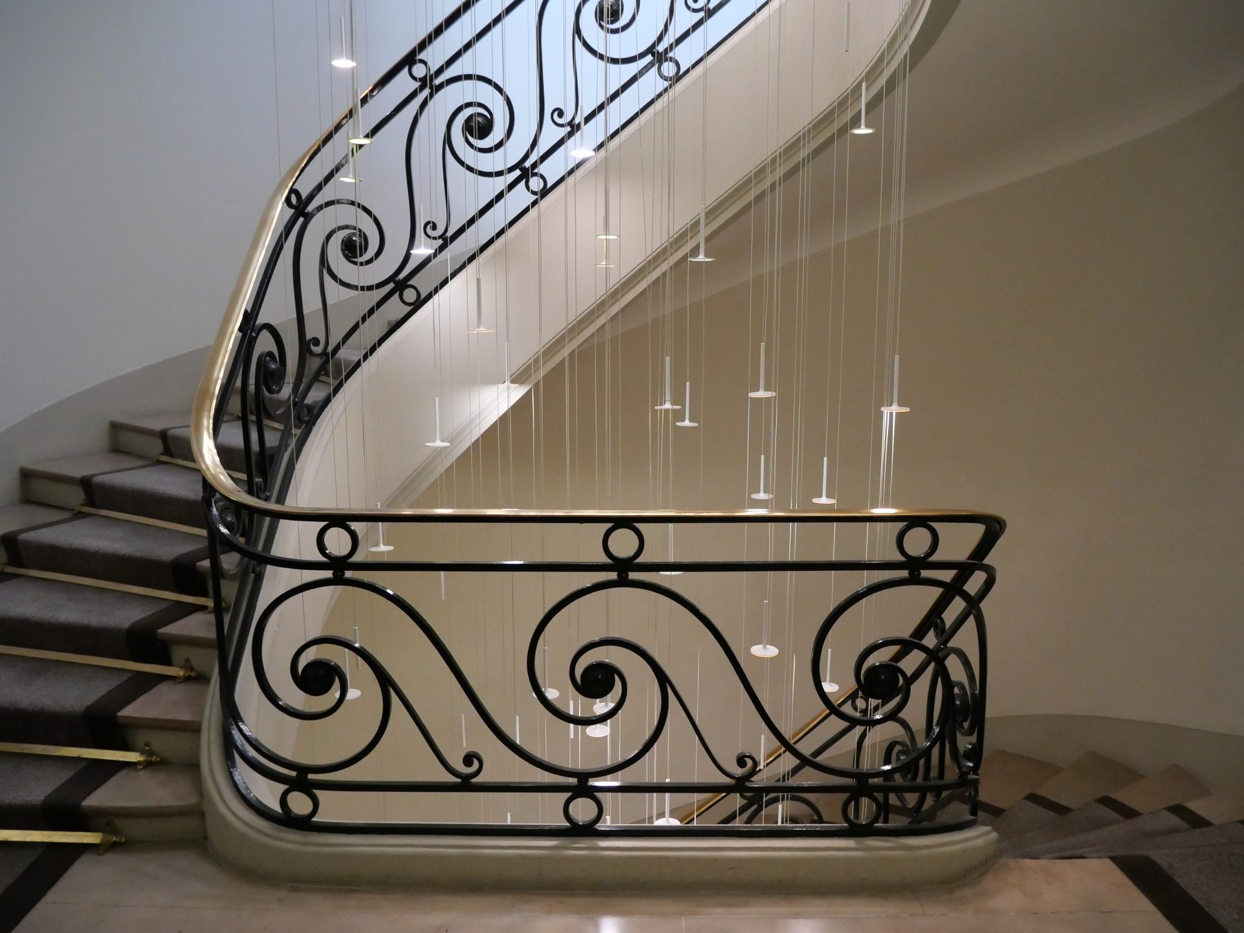 Escalier d’honneur restauré, garde-corps en ferronnerie et main courante laiton